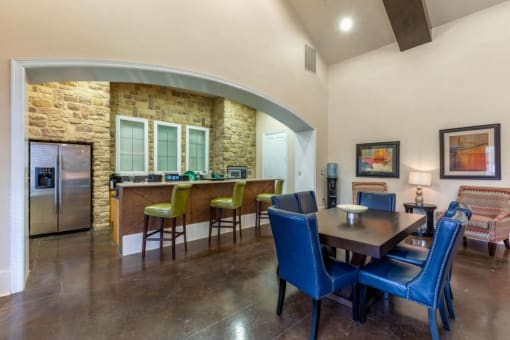 Clubhouse kitchen with a large wooden table, blue chair, and a kitchen island