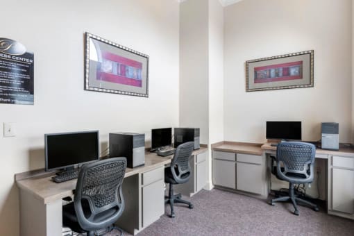 Business Center with computer lab, three chairs, framed photos on the walls, and tan and cream desks