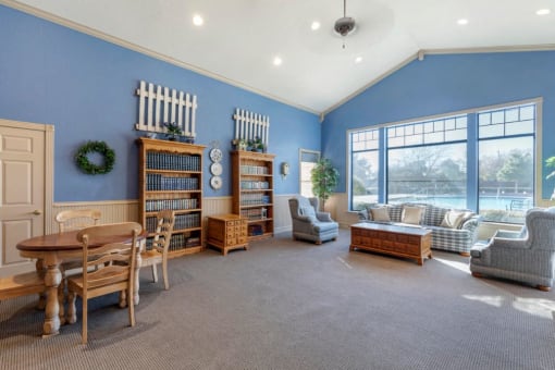 Resident lounge area with blue walls, vaulted ceilings, wooden furniture, and a couch with an accent chair