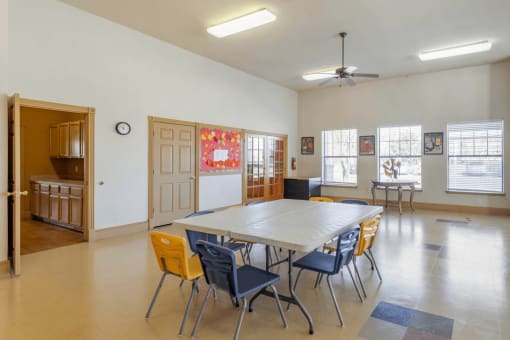 Activity room with tables and chairs, ceiling fan, and tile flooring