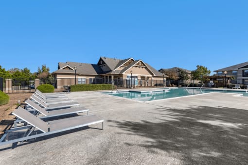 Swimming pool with large tanning deck, lounge chairs, pergola and native surrounding landscape