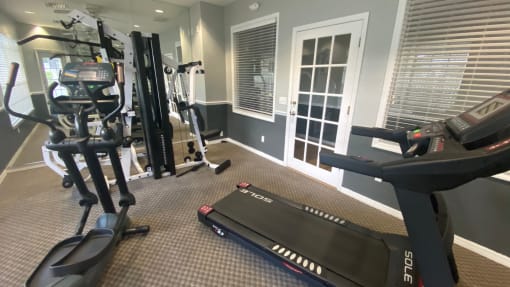 Carpeted fitness center with treadmill, elliptical, weight machines, and dual tone paint