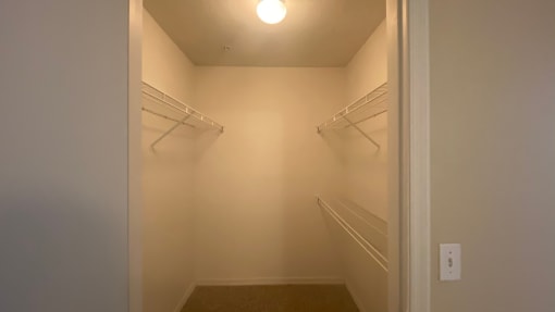 Spacious single door closet with mounted metal shelves