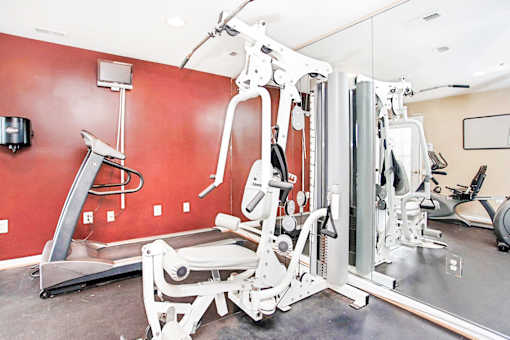A gym with a red wall and a variety of equipment.