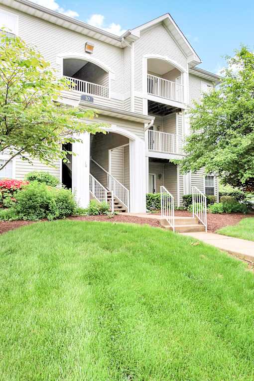A white two-story apartment building with a balcony on the second floor.
