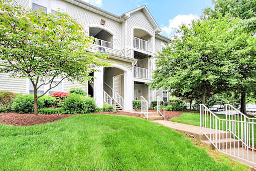 A white two-story apartment building with a balcony on the second floor.