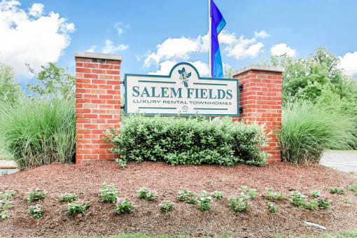 Community Entrance Sign with Shrubs and trees in background