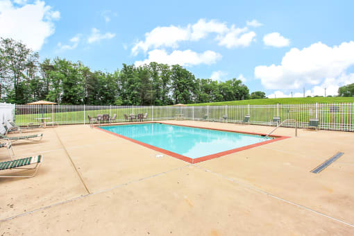 Pool area with outdoor seating. Pool lounge chairs and umbrellas in background.