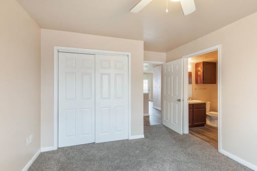 Bedroom with en-suite bathroom, closet, and ceiling fan