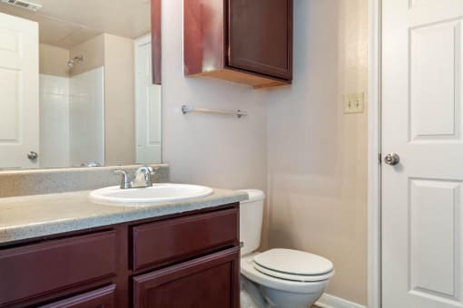 Bathroom with wooden cabinetry and towel bar behind toilet