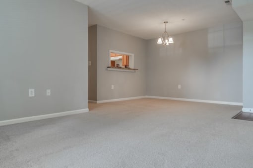 Empty living room and dining with carpet and dining chandler