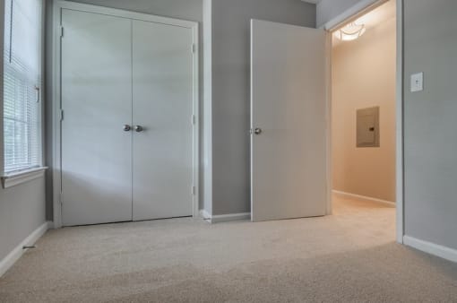 Empty bedroom with carpet, closet and window