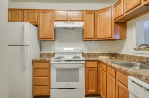 Kitchen with wood cabinets, granite style countertops, and white appliances