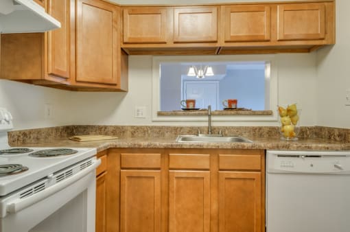 Kitchen with wood cabinets, granite style countertops, and white appliances