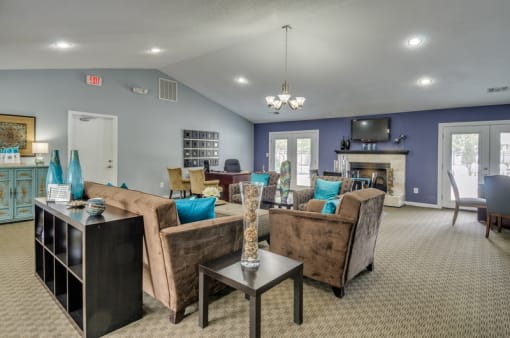 Leasing office interior waiting area with a couch, two chairs, dining table with chairs, and kitchen area