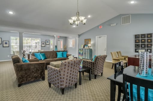 Leasing office interior waiting area with a couch, two chairs, dining table with chairs, and kitchen area