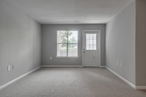 Empty living room with carpet, exterior door and window