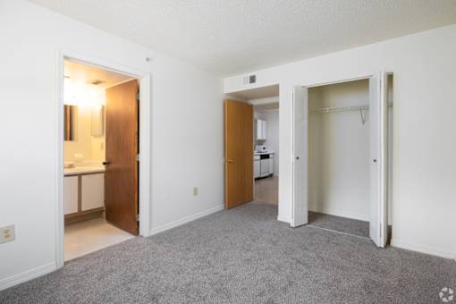 A room with a carpeted floor and two open doors.
