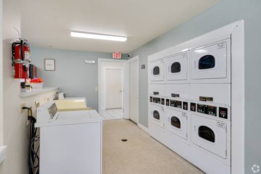 A laundry room with a washer and dryer, a door, and a recycling bin.
