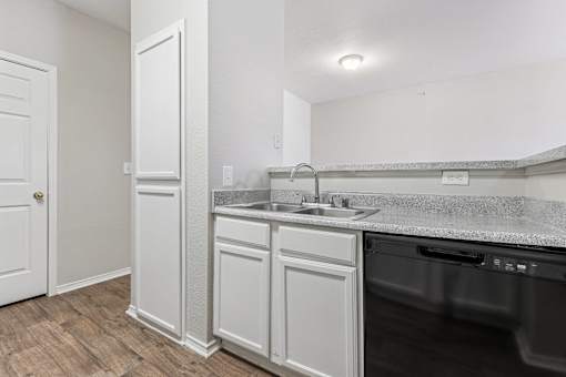 A kitchen with a white cabinet and a black dishwasher.