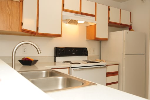 The furnished model home has hardstyle flooring in the entry by the front door with carpet in the living room and dining room. This floorplan is an open. There is a gray upholstered couch, a tan, blue, and red patterned chair, a dark wooden coffee table, a round dining table with 4 chairs and framed artwork hanging on the walls.
