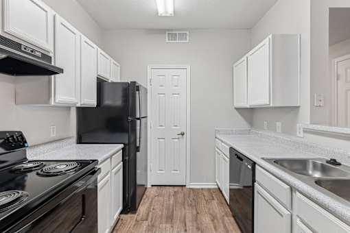 A kitchen with black appliances and white cabinets.
