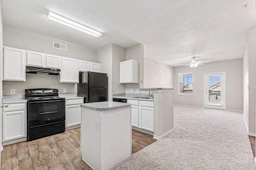 A kitchen with white cabinets and black appliances.