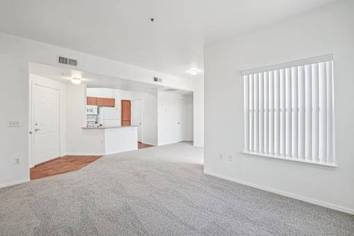 Spacious living area with kitchen and carpet at Lake Pleasant Village Apartments, Peoria, AZ 85382