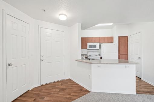 Kitchen with white appliances and breakfast bar at Lake Pleasant Village Apartments, Peoria, AZ