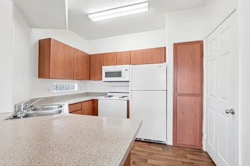 Kitchen with wood cabinets and white appliances at Lake Pleasant Village Apartments, Peoria, 85382
