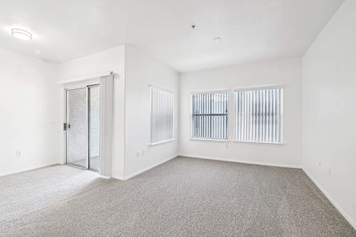 Empty carpeted room with sliding glass door at Lake Pleasant Village Apartments, Arizona