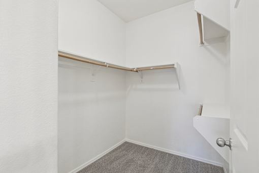 Walk-in closet with carpet and hanging rod at Lake Pleasant Village Apartments, Peoria, AZ 85382