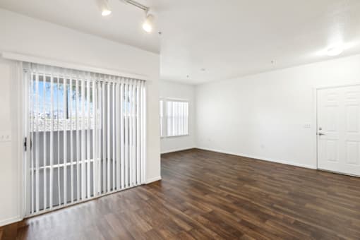 an empty living room with wood flooring and a sliding glass door