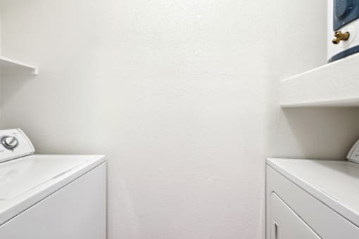 a white washer and dryer in a white laundry room with white walls