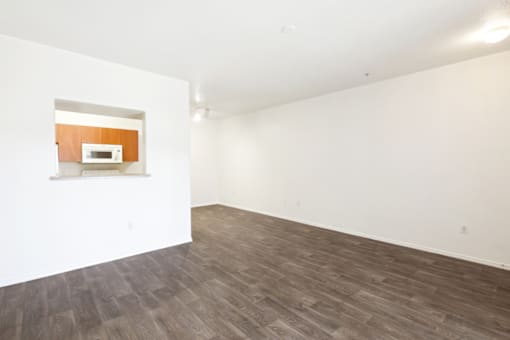 an empty room with white walls and wood flooring and a microwave in the corner