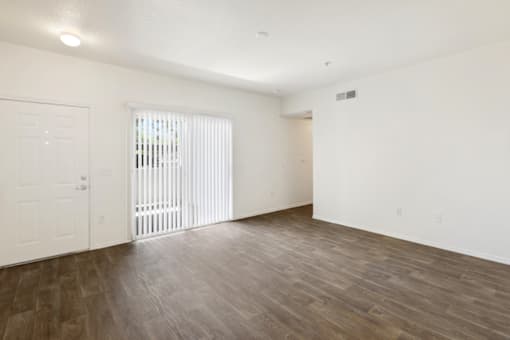 the living room of an apartment with white walls and wood flooring