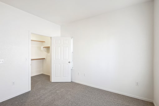a bedroom with white walls and a closet and a white door
