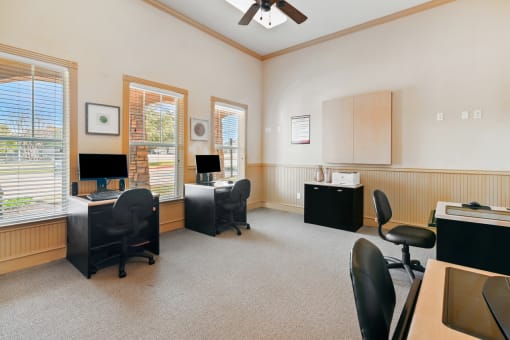 a room with two desks and two chairs and a ceiling fan