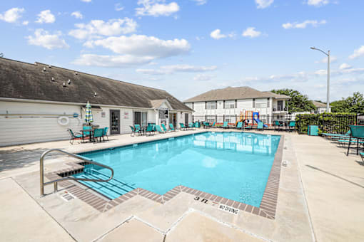 A large outdoor swimming pool with a slide and lounging chairs.