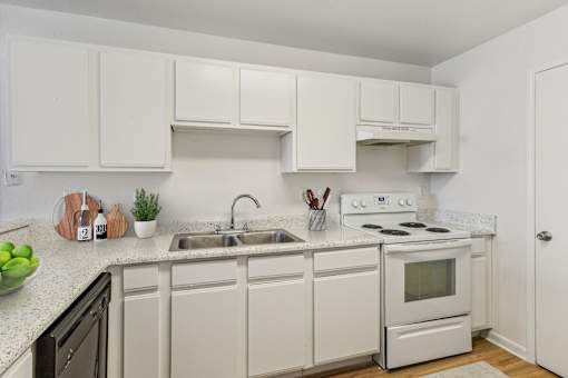 A white kitchen with a black dishwasher and white appliances.
