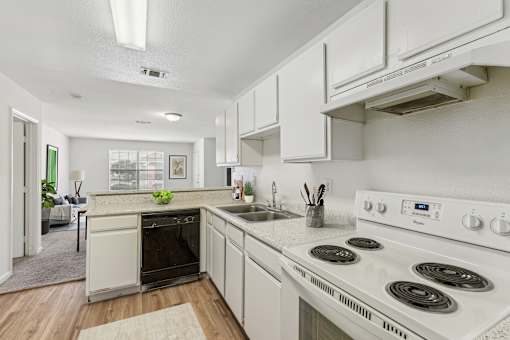 A white kitchen with a stove top oven and a sink.