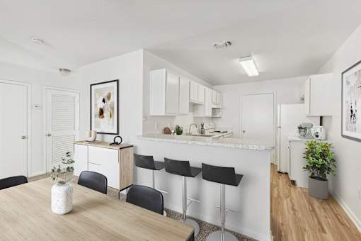 A kitchen with white cabinets and a wooden table.