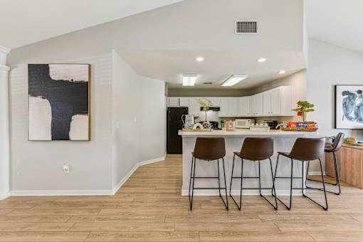 A kitchen with a bar area and chairs.