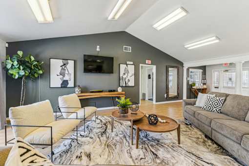 A living room with a grey couch, a white chair, and a wooden coffee table.