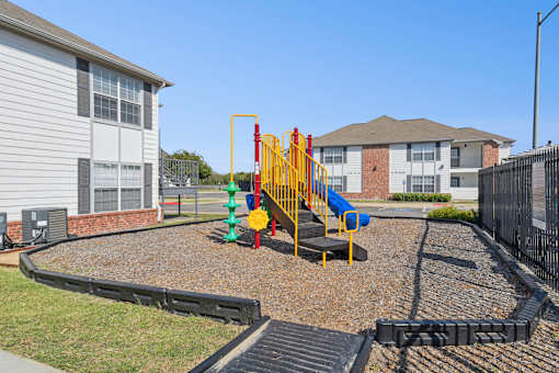 A playground with a yellow slide and a red and blue climbing frame.