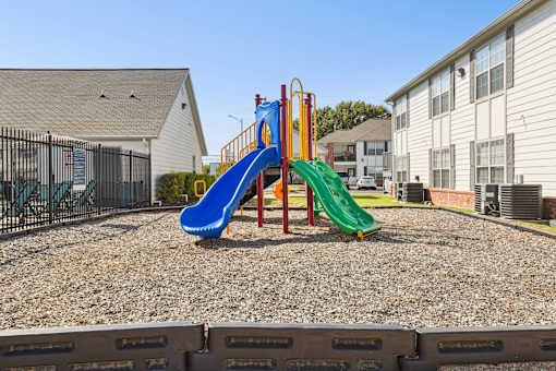 A playground with a blue slide and a green slide.