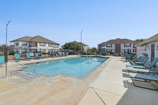 A swimming pool surrounded by lounge chairs and umbrellas.