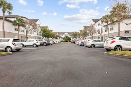 a parking lot filled with cars in front of apartment buildings