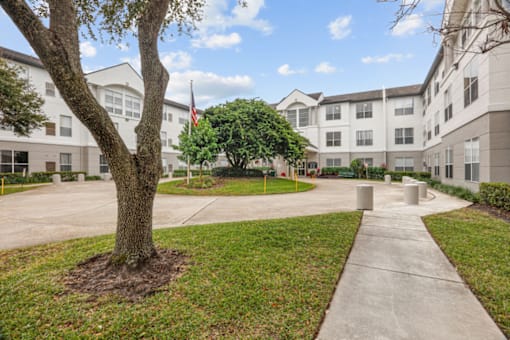 an apartment building with a sidewalk and tree in front of it