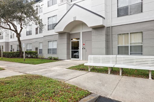 a white bench in front of a building with a door